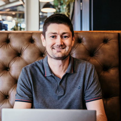 Mathew sitting in front of his laptop smiling at the camera.